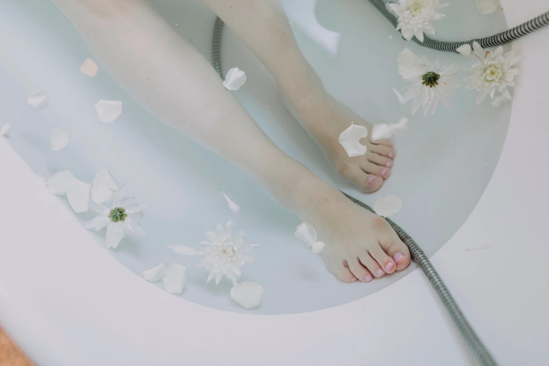 Feet immersed in water in a white basin